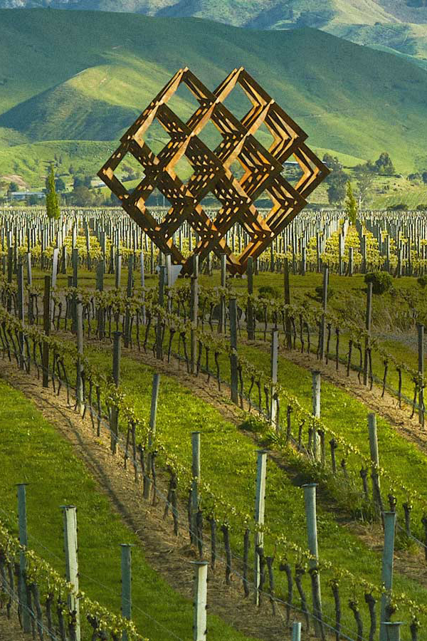 Geometrische Skulptur ragt über Weinreben